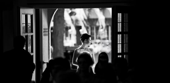 Bride standing in the doorway in the sunlight.