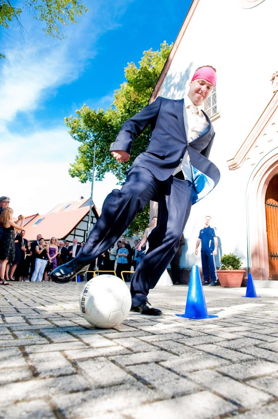 Man in a suit playing soccer at a party.