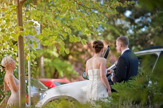 Bridal couple and guest in conversation outdoors