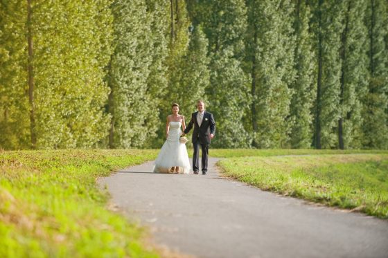 Bride and groom walk along a forest path