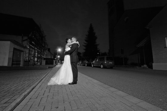 Couple hugging on the street at night.