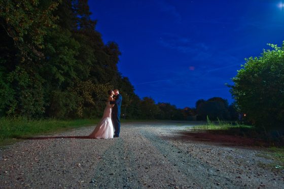 Bride and groom dancing outdoors at night under a blue sky.