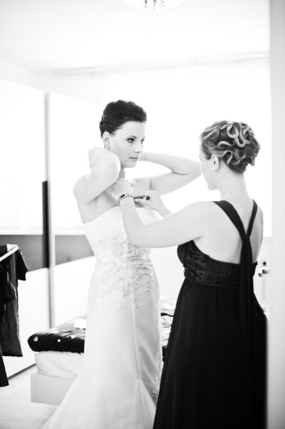 Bride being helped to dress by friend.