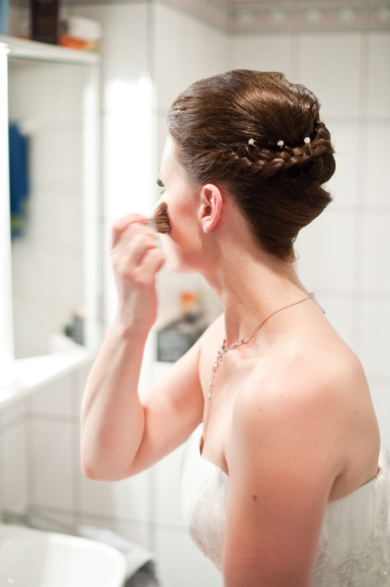 Bride applies make-up in the bathroom mirror