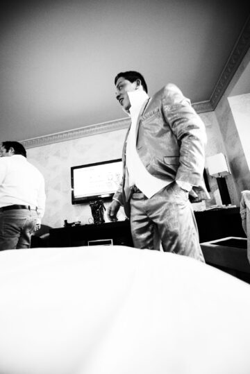 Männer in Anzügen vor Fernseher im Hotelzimmer