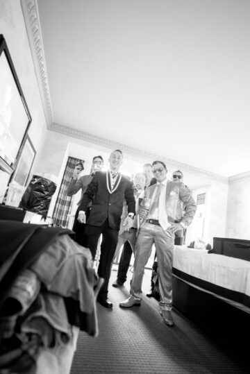 Männer in Anzügen feiern im Hotelzimmer.