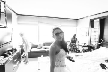 Lächelnde Frau mit Sonnenbrille in einem Zimmer.